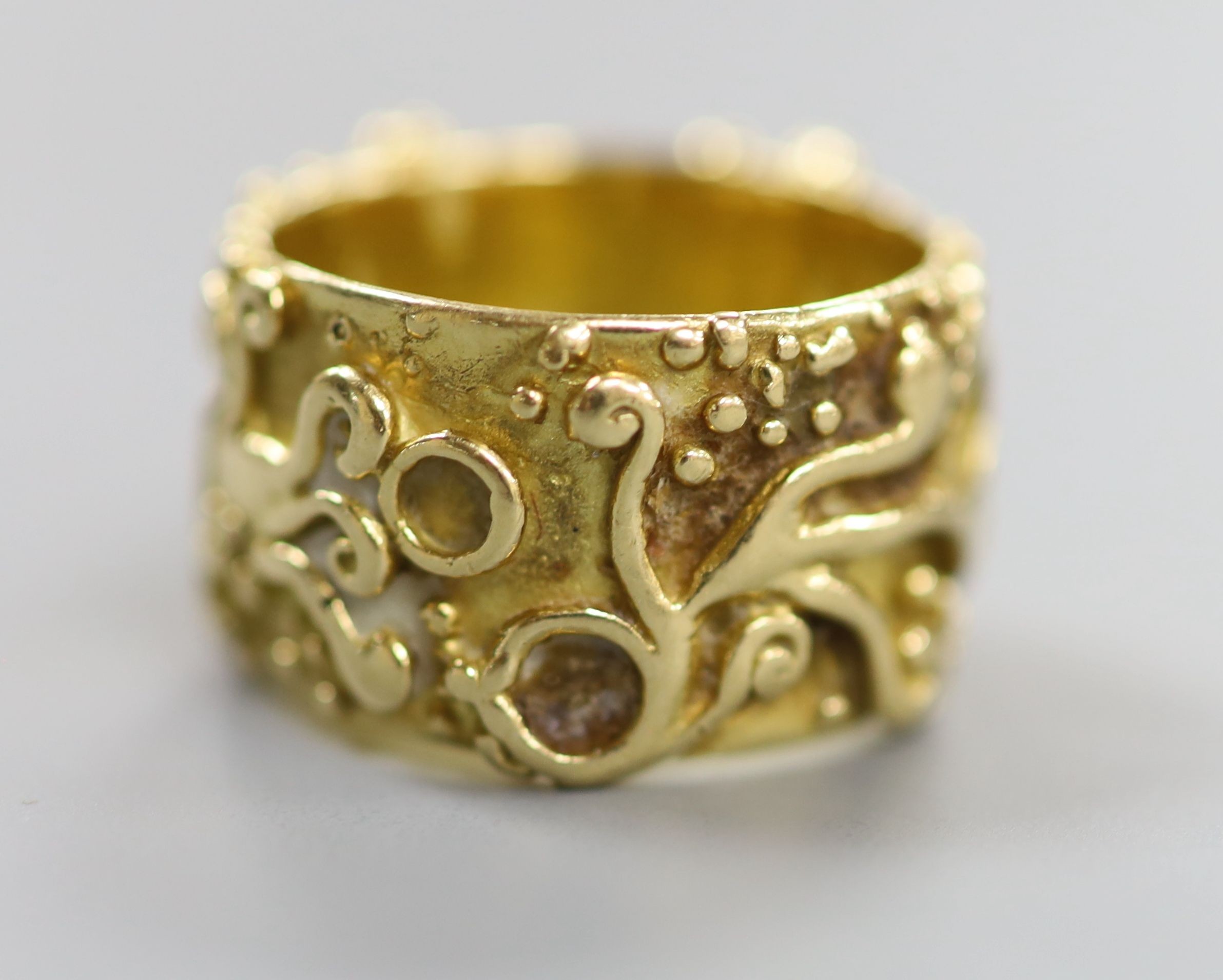 An 18ct Welsh gold band, with pierced and scroll decoration, size O, 11.8 grams.